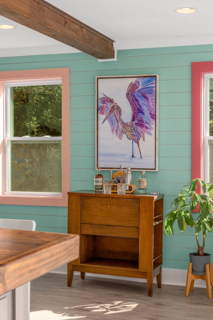 Purple Heron painting by local artist against mint green shiplap walls above custom bar with cocktail set.