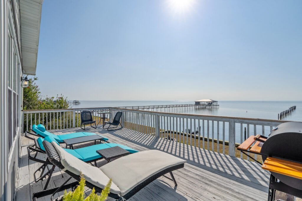3 o'clock sun warming back deck with sun chairs overlooking calm waters of the bay.