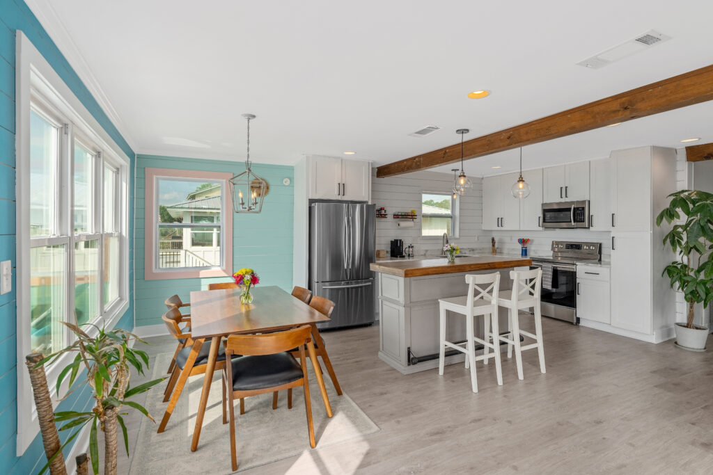 Open kitchen and dining area accented by wood tabletops and celing beams, stainless steel appliances and love houseplants.