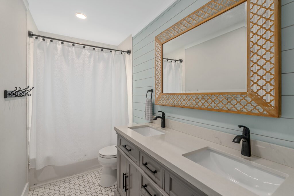 Double vanity sinks with bronze faucets and quartz counter in full bathroom.