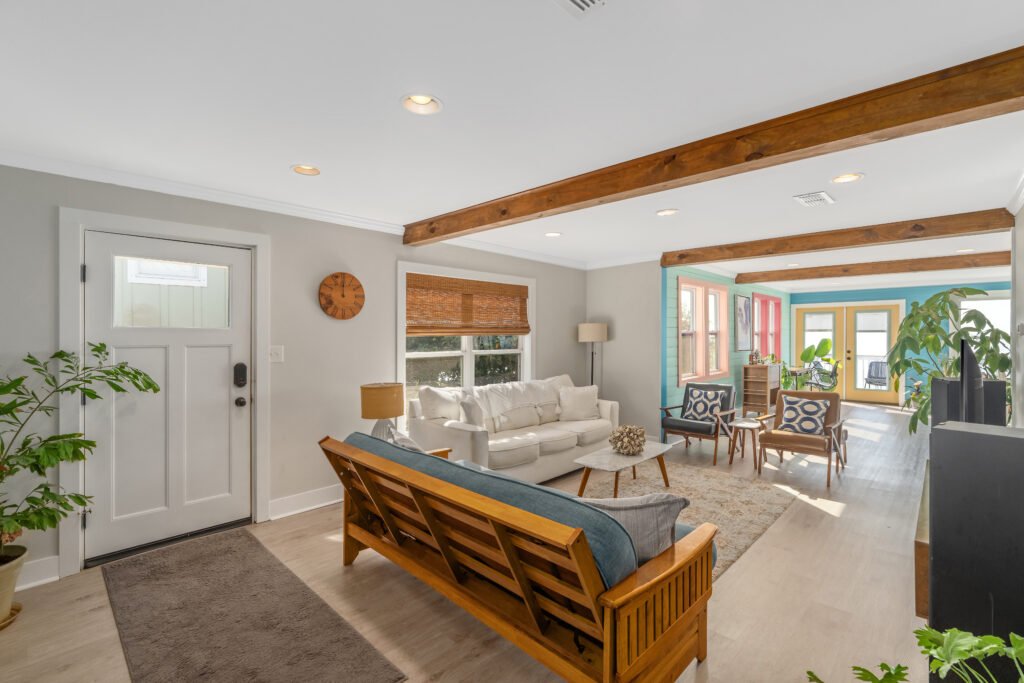Wood ceiling beams overlook sitting area in living room with matching bamboo blinds.