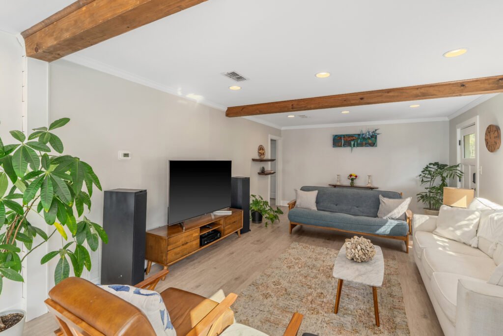 Plush futon, white sleeper sofa and two leather sitting chairs surround marble coffee table for gathering and entertainment.