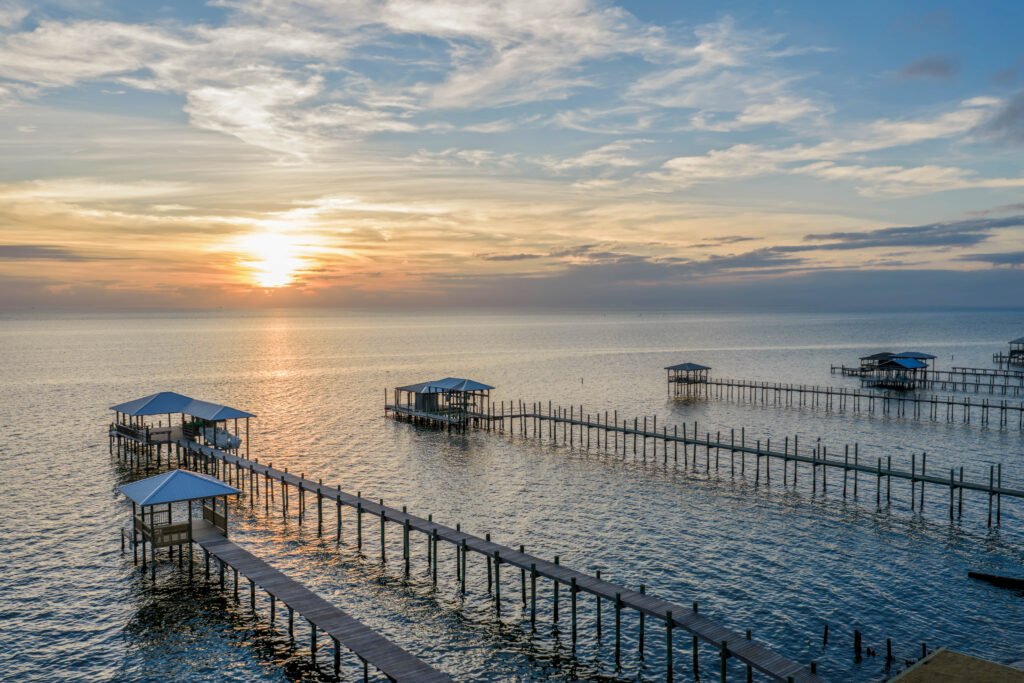 Fiery Mobile Bay sunset activates evening skies above bay house wharfs and piers.