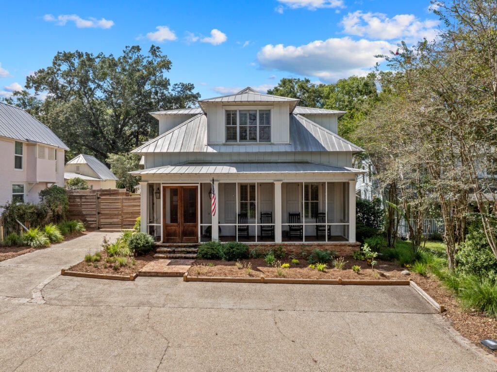Front parking and private porch of 4 bedroom luxury cottage rental in downtown Fairhope on a sunny day.
