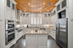 As cottages or Fairhope do, Emerson House kitchen features shiplap walls, pine board ceilings and custom wainscoting