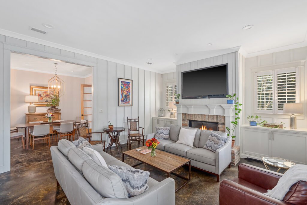 Living room featuring leather sofas, decorative concrete floors and large tv over mantle.