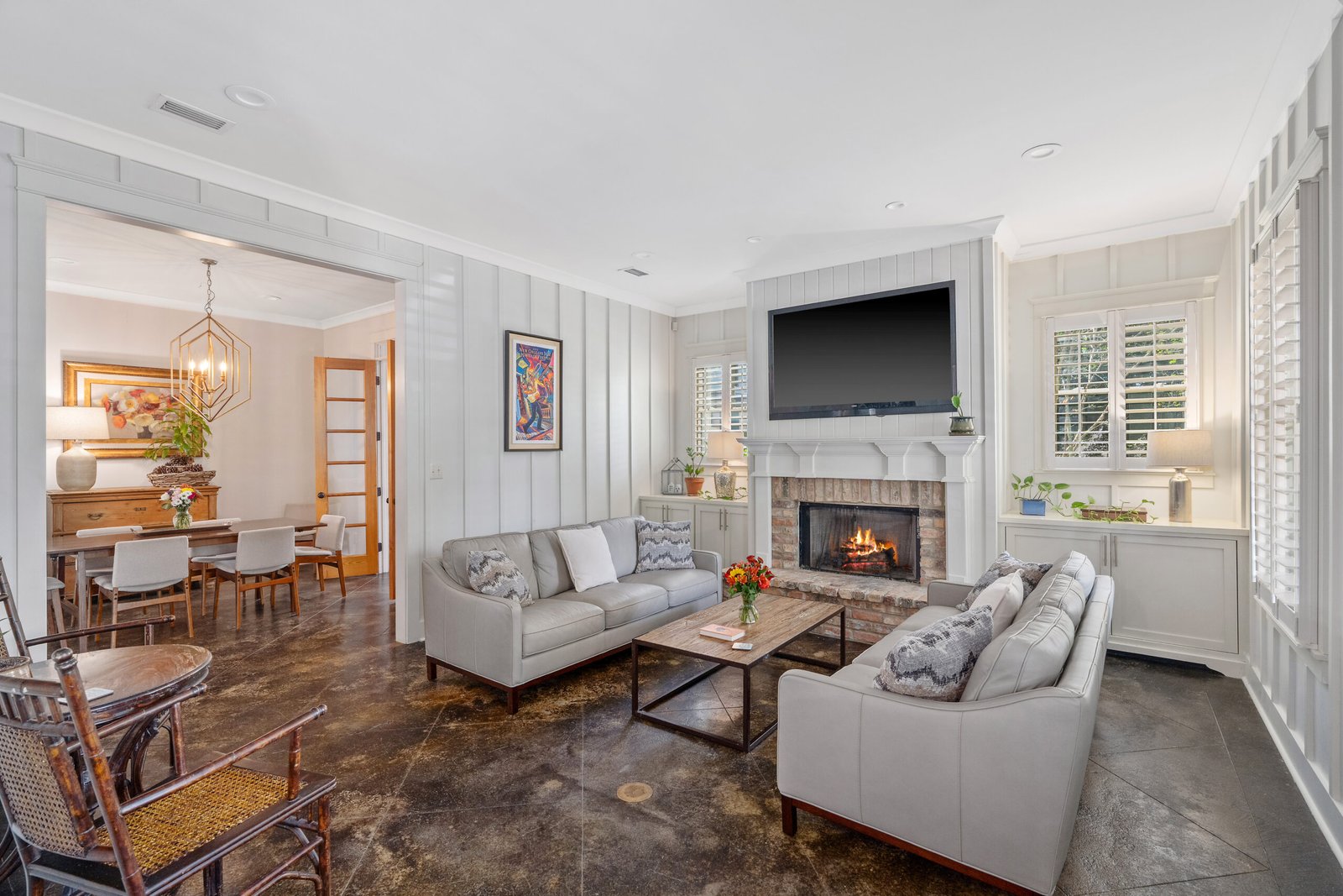 Luxury living room with comforting fireplace and leather sofas featuring bay house style batten walls. 