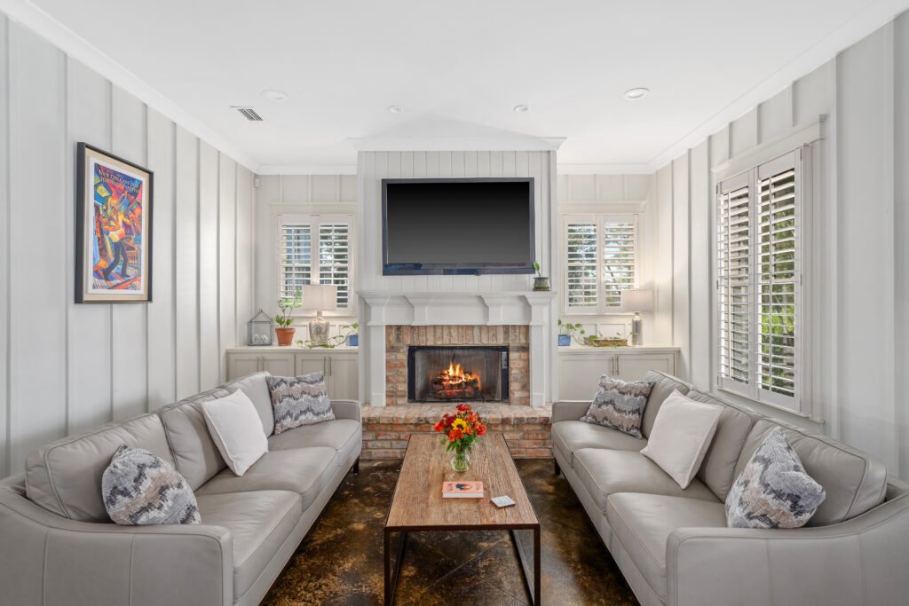 Bay house style batten walls encapsulate upscale living room with cozy fireplace, large TV and leather sofas.