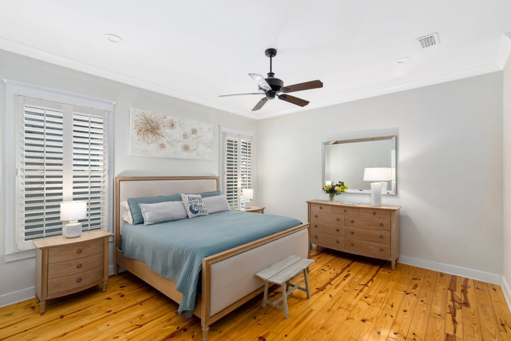 Master bedroom shows king bed, night tables and dresser. Custom artwork and ceiling fan.