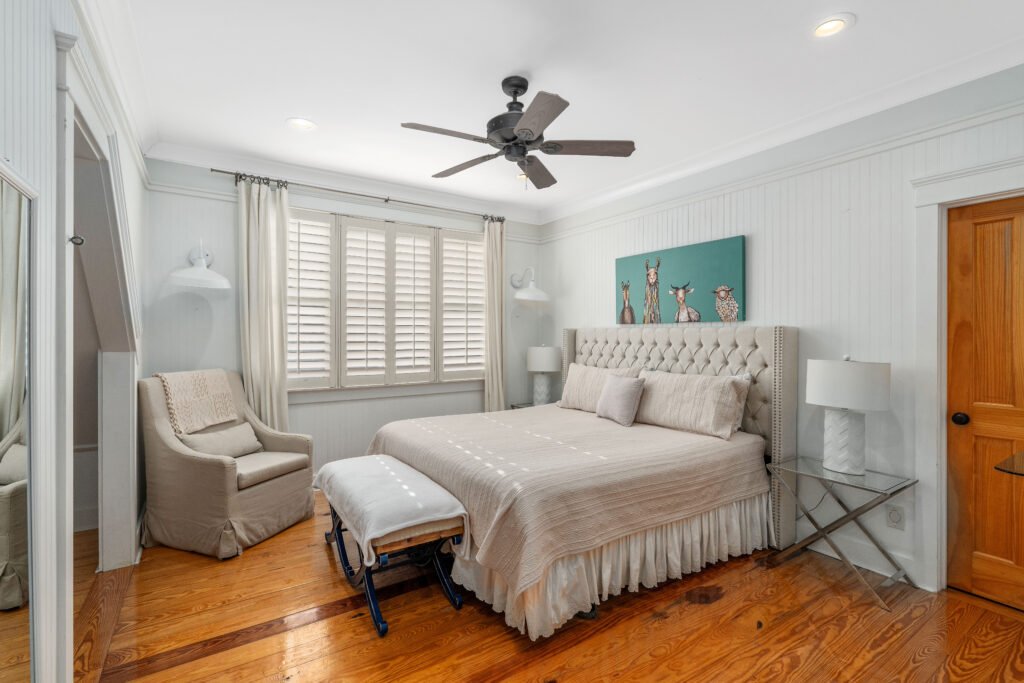 Close view of king bed and resting chair in upstaris bedroom with knotty pine finished wood floors.