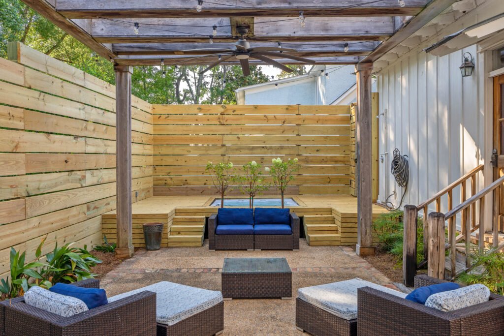 Close center view of back yard patio featuring outdoor seating, new deck and hot tub. Potted limelight hydrangeas are blooming.