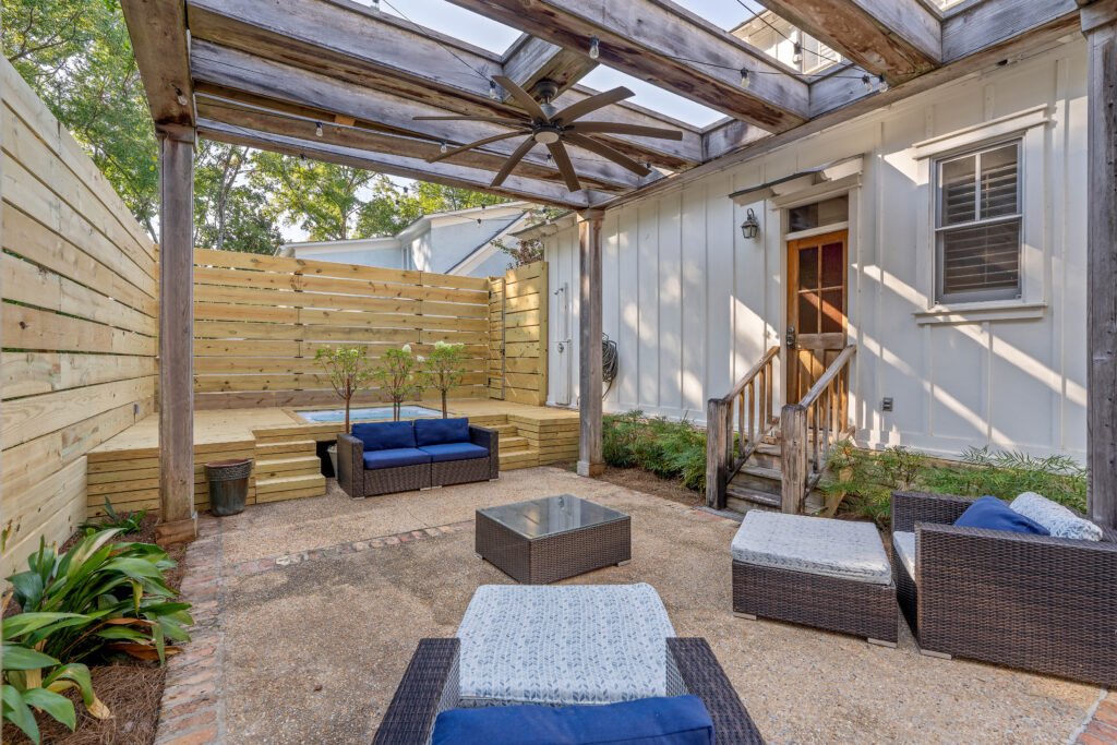Angle view of rear patio seating, hot tub and back of Emerson House with outdoor seating.