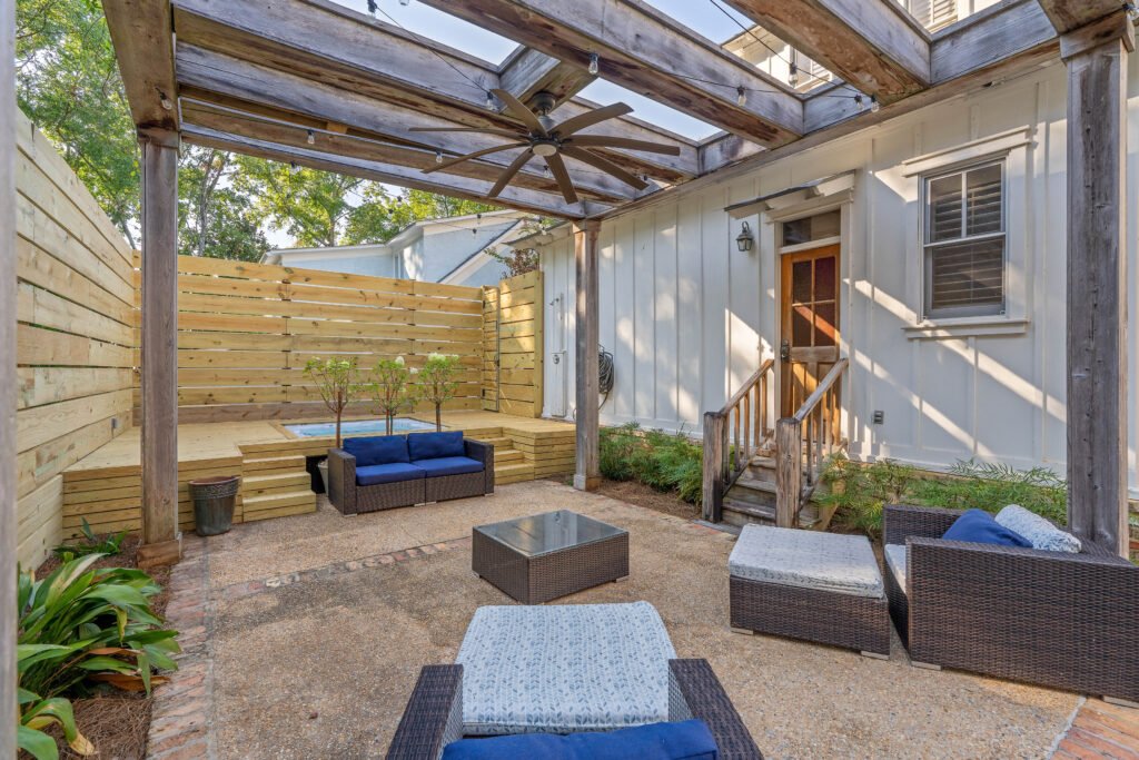 Angle view of rear patio seating, hot tub and back of Emerson House with outdoor seating and pergola.