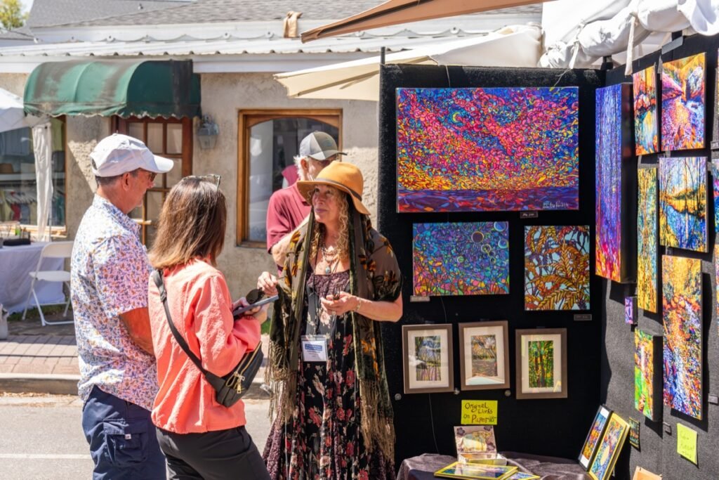 Visitors browse vivid abstract paintings at an artist booth during the Fairhope Arts and Crafts Festival 2026